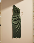 Olivgrünes One-Shoulder-Abendkleid mit Drapierung auf einem Kleiderbügel vor hellem Hintergrund präsentiert.