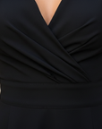 Close-up of black evening dress bodice showing wrap-style neckline, smooth fabric, and structured stitching.