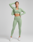 Mintgrünes Sportset mit figurbetontem Crop-Top und hoher Leggings, getragen in heller Studioaufnahme.