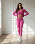 Pinkes zweiteiliges Sportset bestehend aus Crop-Top und Leggings flach ausgelegt auf hellem Hintergrund, kombiniert mit Sneakers.