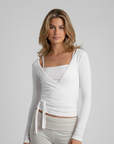Weißes Wickeltop mit elegantem Ausschnitt und figurbetonter Linienführung, präsentiert im neutralen Studio.