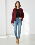 Burgunderrote Damenjacke mit strukturierter Oberfläche, getragen in entspannter Pose vor hellem Hintergrund.