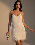 Frau trägt ein weißes Feder-Minikleid mit Spaghettiträgern und verspielter Party-Silhouette
