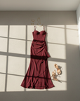 Bordeauxfarbenes Abendkleid flachgelegt mit Sandalen und Schmuck