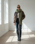 Flach ausgelegtes Outfit mit brauner Lederjacke, Jeans und Accessoires, stilvoll arrangiert für eine elegante Präsentation.