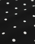 Nahaufnahme des schwarzen Stoffes mit weißen Polka-Dots und weicher, glatt fallender Textur.