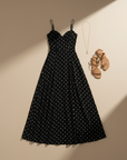 Schwarzes Maxikleid mit weißen Punkten und zarten Trägern flach ausgelegt neben Accessoires auf hellem Hintergrund.