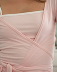 Nahaufnahme eines rosa Wickeltops mit weichem Stoff, feinen Falten und elegantem Wickel-Detail.