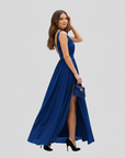 Female model in a blue slit maxi dress featuring a wrap-style top and flowy skirt in studio lighting.