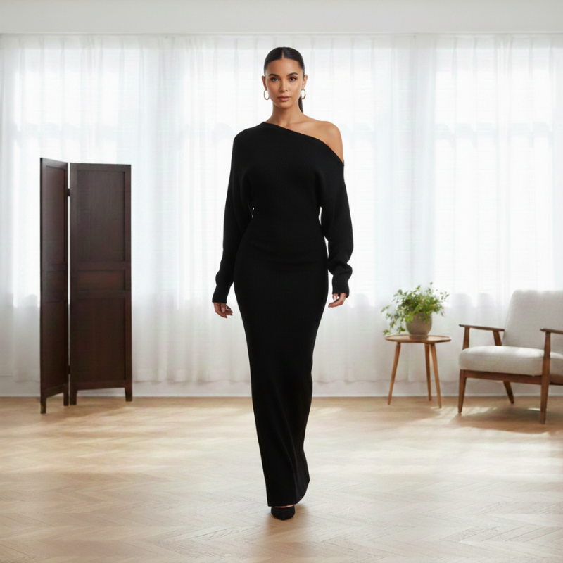 Model trägt ein schwarzes, langes Kleid mit weitem Schnitt und klarer Silhouette in einem hellen Innenraum.