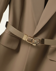 Nahaufnahme des beigefarbenen Blazers mit feiner Textur, goldfarbenem Gürtelverschluss und sauberer Verarbeitung.