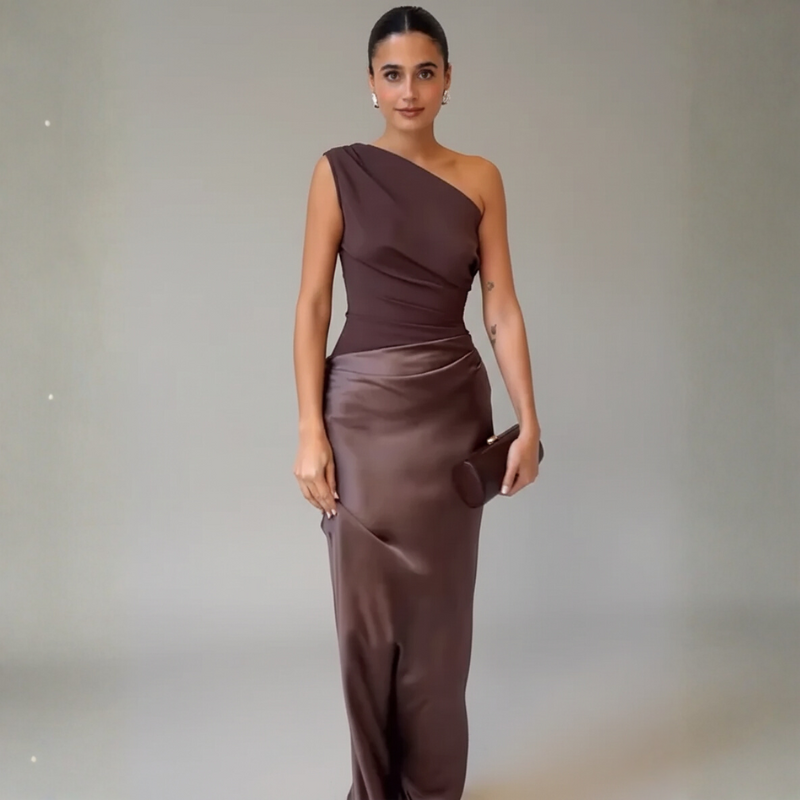 Model trägt ein braunes One-Shoulder-Abendkleid mit gerüschtem Detail und figurbetontem Schnitt im Studio.