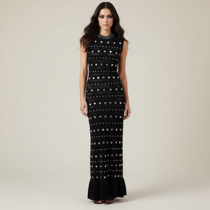 Model trägt ein schwarzes, langes Abendkleid mit aufwendigem Perlen- und Nietenmuster sowie figurbetonter Silhouette im Studio.