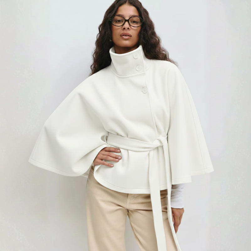 Weißes Cape-Oberteil mit fließender Silhouette und Gürtel, getragen vor neutralem Hintergrund.