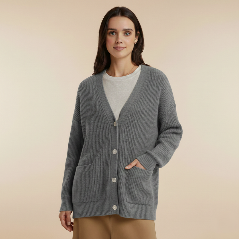 Model trägt einen grauen Strickcardigan mit V-Ausschnitt, Knopfleiste und lockerer Silhouette vor neutralem Hintergrund.