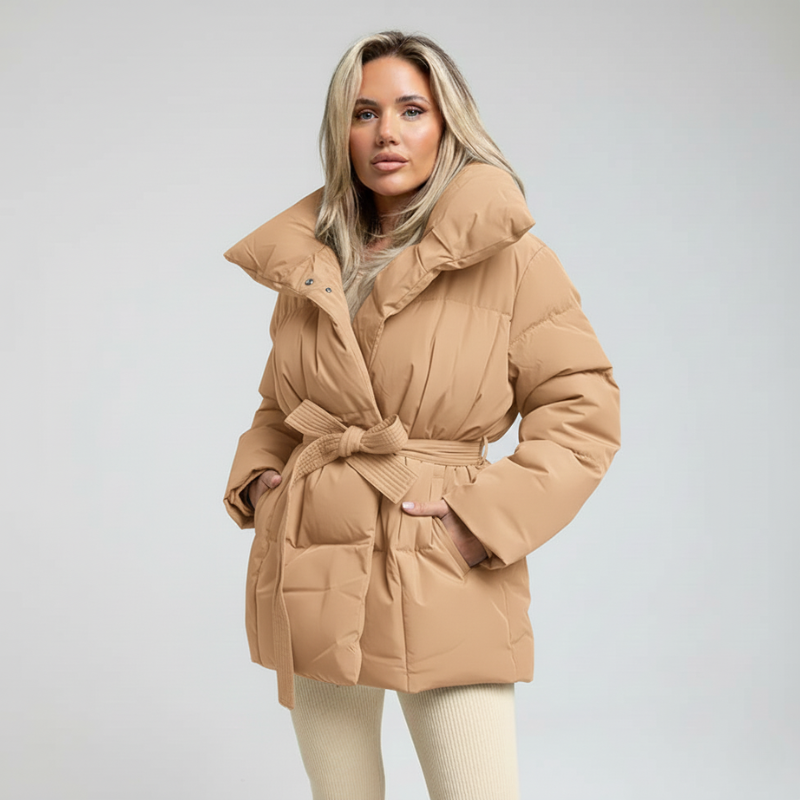 Model trägt eine beigefarbene Damen-Daunenjacke mit Gürtel und hohem Kragen im Studio.