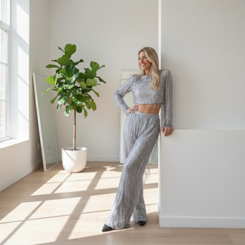 Model trägt ein silbernes Glitzer-Set in einem lichtdurchfluteten Innenraum mit moderner Einrichtung.