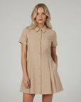 Beiges kurzes Hemdblusenkleid mit Knopfleiste, Kurzärmeln und sanft ausgestelltem Rock, getragen im neutralen Studio.