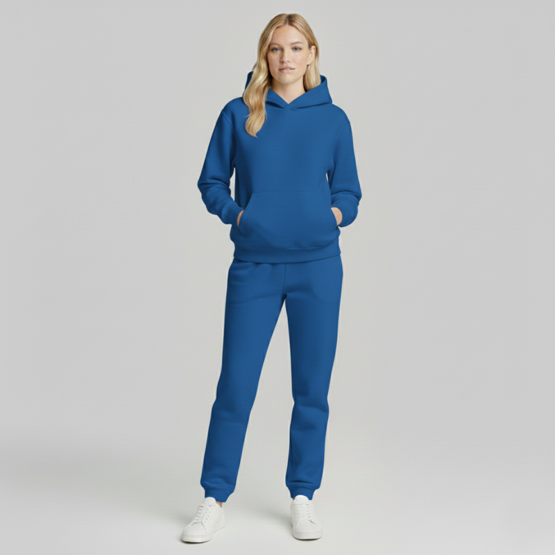 Frau in blauem Hoodie-und-Jogger-Set, aufgenommen im Studio in voller Körperansicht.
