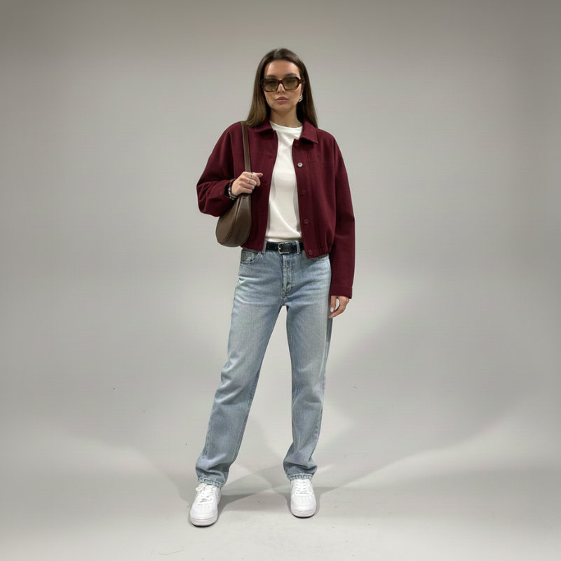 Bordeauxrote Damenjacke mit strukturierter Oberfläche, kombiniert mit Jeans in einer Studioaufnahme.