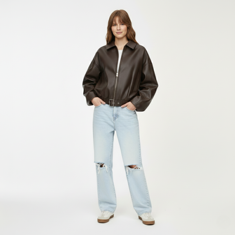 Modell steht in schwarzer Lederjacke und hellen Jeans auf weißem Hintergrund im professionellen Fotostudio.