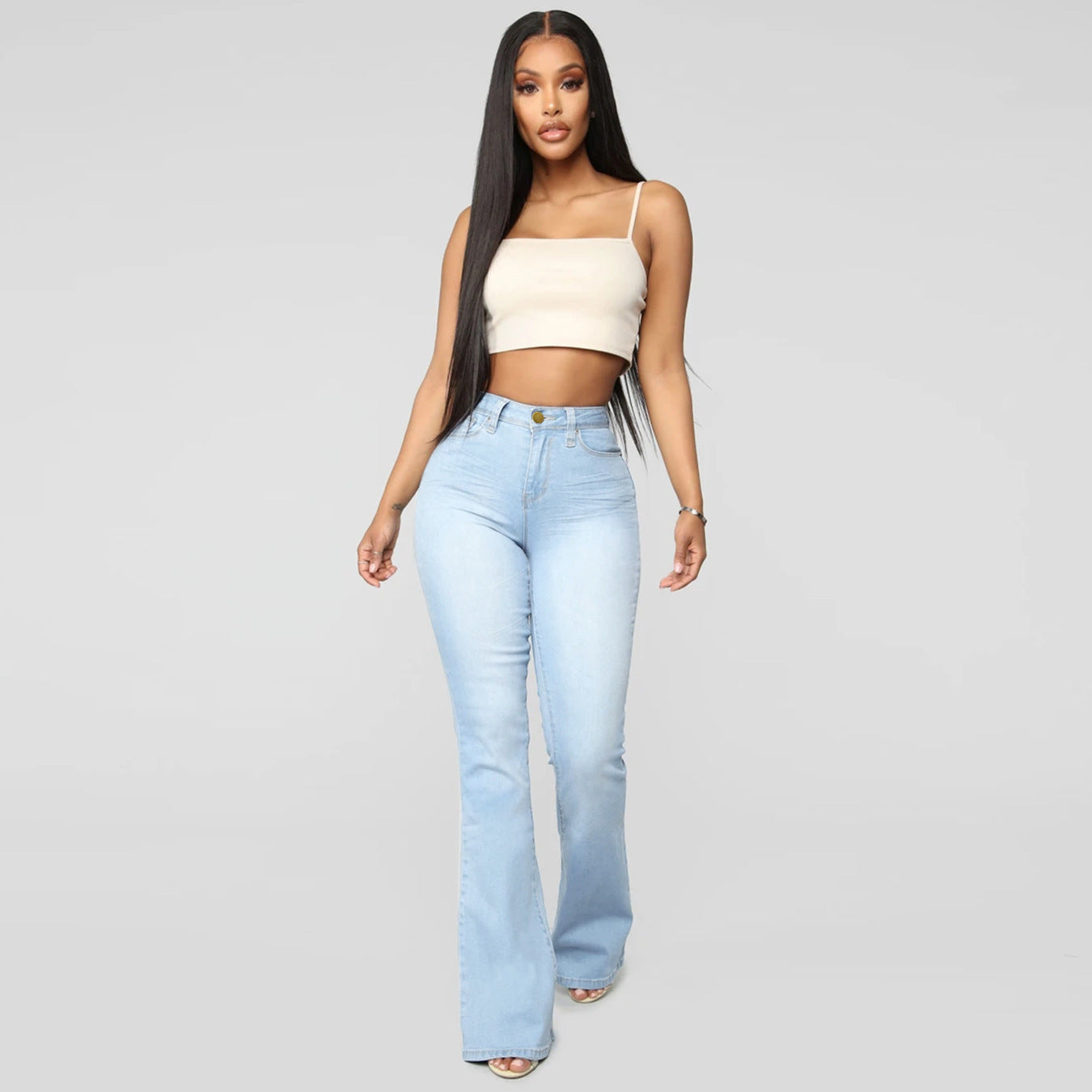 Modell trägt eine hellblaue Bootcut-Jeans mit hohem Bund und weißem Top.