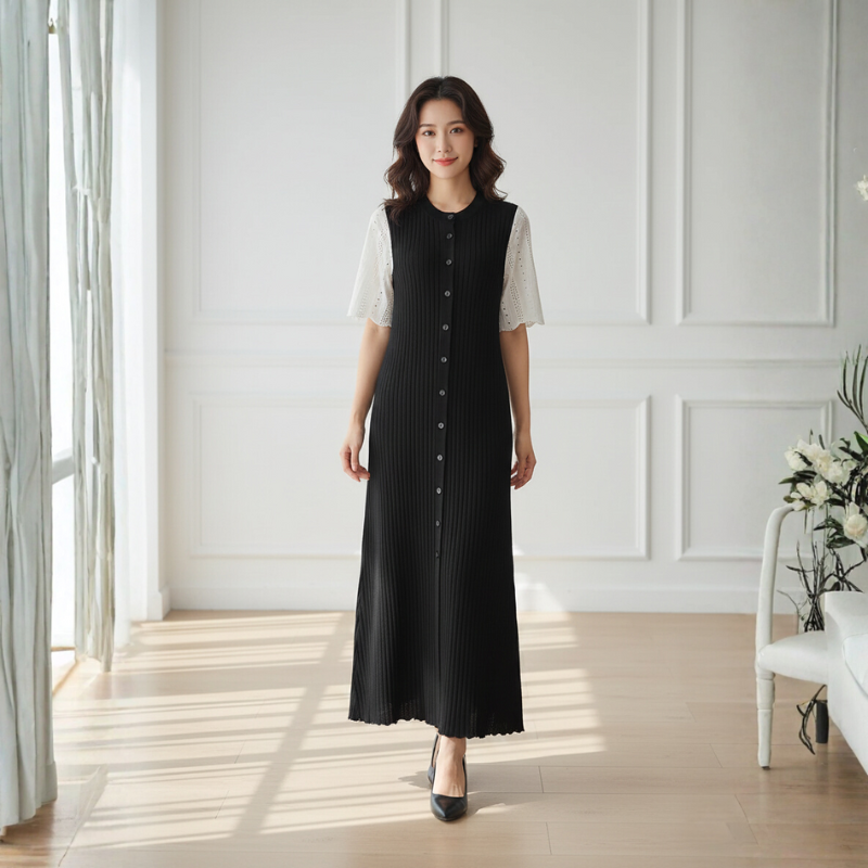 Langes schwarzes Kleid mit ärmelloser Form und schlichter, moderner Linienführung in einer hellen Innenraumszene.