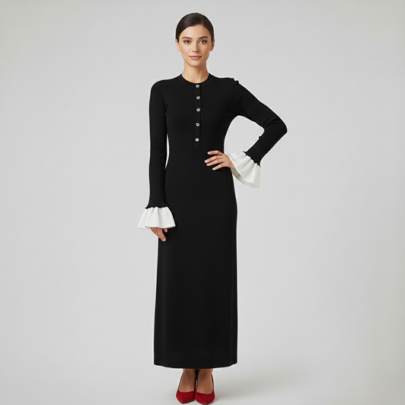 Langes schwarzes Kleid mit goldenen Knöpfen, ausgestellter Silhouette und kontrastierenden Manschetten in heller Studioaufnahme.