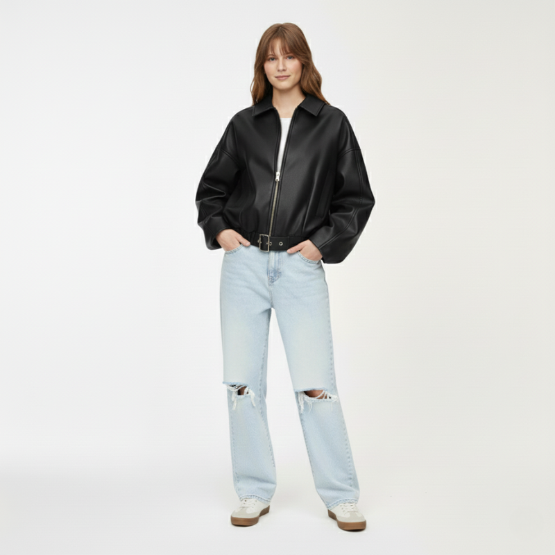 Modell trägt eine schwarze Lederjacke kombiniert mit hellem Shirt und Jeans im Studio.