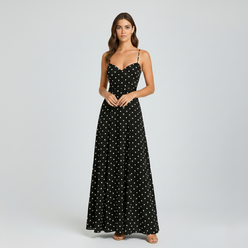 Model trägt ein schwarzes Maxikleid mit weißen Polka-Dots, feinen Spaghettiträgern und fließender Silhouette im Studio.