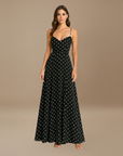 Schwarzes Maxikleid mit weißen Punkten, feinen Trägern und eleganter Silhouette, präsentiert im neutralen Studio.