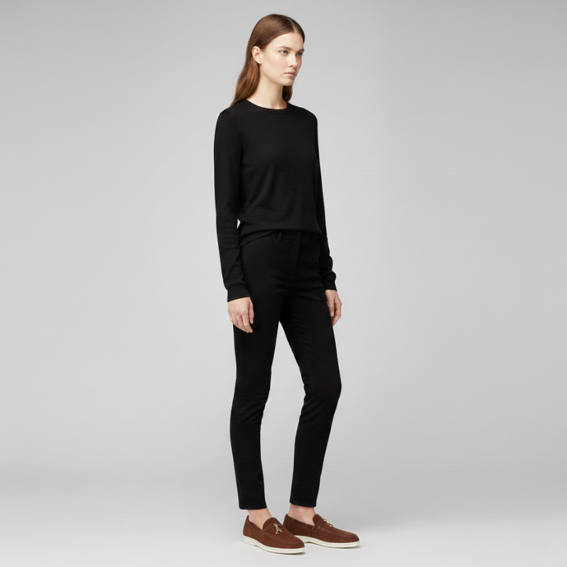 Modell trägt ein komplett schwarzes, minimalistisches Outfit mit flachen Loafern in neutralem Studio.