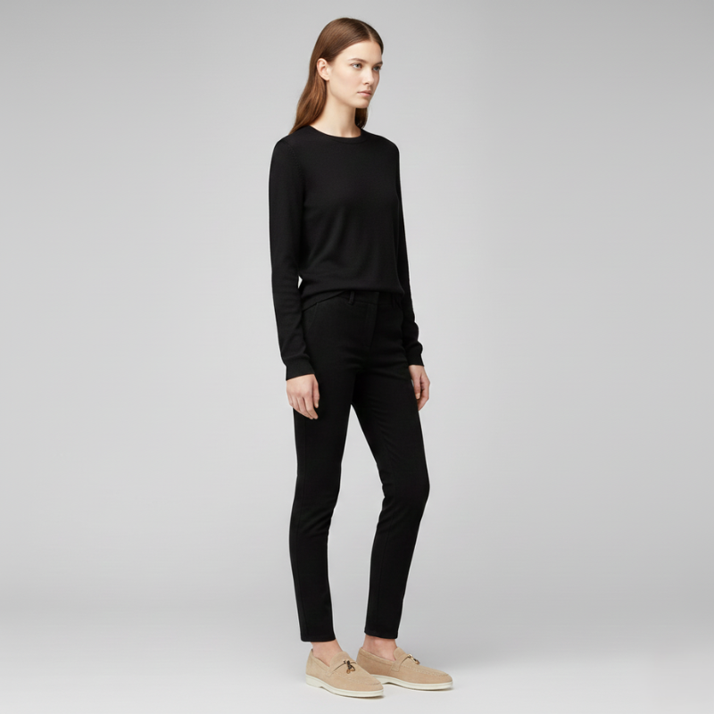 Modell in schwarzem Oberteil und schwarzer Hose in seitlicher Studioaufnahme mit cleanem Licht.