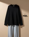Rückansicht eines schwarzen Oversize-Pullovers mit weiter Silhouette und minimalistischem Design im hellen Studio.