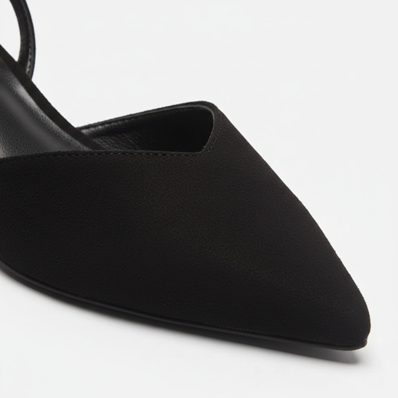 Nahaufnahme einer schwarzen spitzen Pumpe mit glatter Oberfläche und eleganter Formgebung.