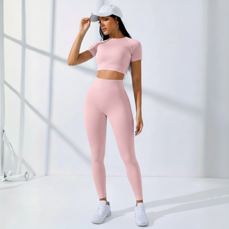 Modell trägt ein rosa Sport-Set mit Crop-Top und Leggings in heller Umgebung.