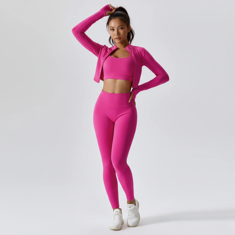 Model trägt ein pinkfarbenes zweiteiliges Sportset mit Crop-Top und hoch taillierter Leggings in klarer Studioaufnahme.