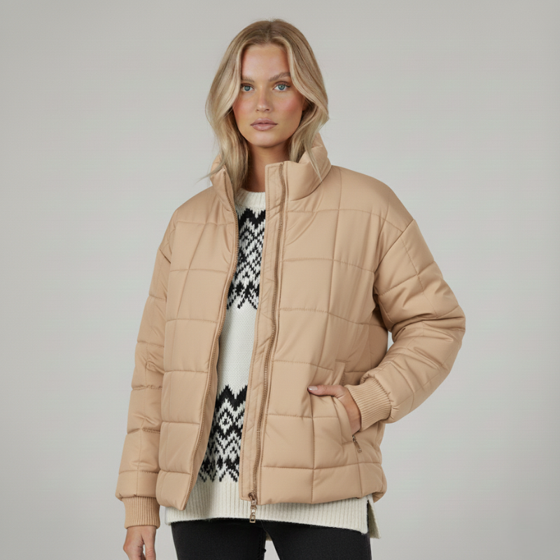 Model trägt eine beige Steppjacke mit hohem Kragen, seitlichen Taschen und klassischer Silhouette im neutralen Studio.