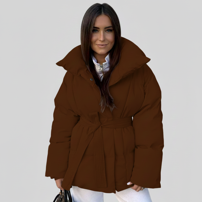 Model trägt eine braune Steppjacke mit Kapuze und sportlich-eleganter Passform im Studio.