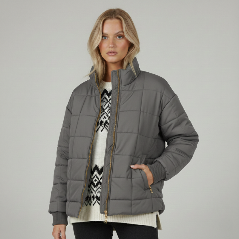 Graue Steppjacke mit klassischem Kragen, glatter Silhouette und funktionaler Linienführung in neutraler Umgebung.