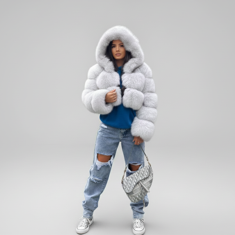 Frau trägt eine helle Steppjacke mit Kapuze, kombiniert mit Jeans in einem lichtdurchfluteten Innenraum.