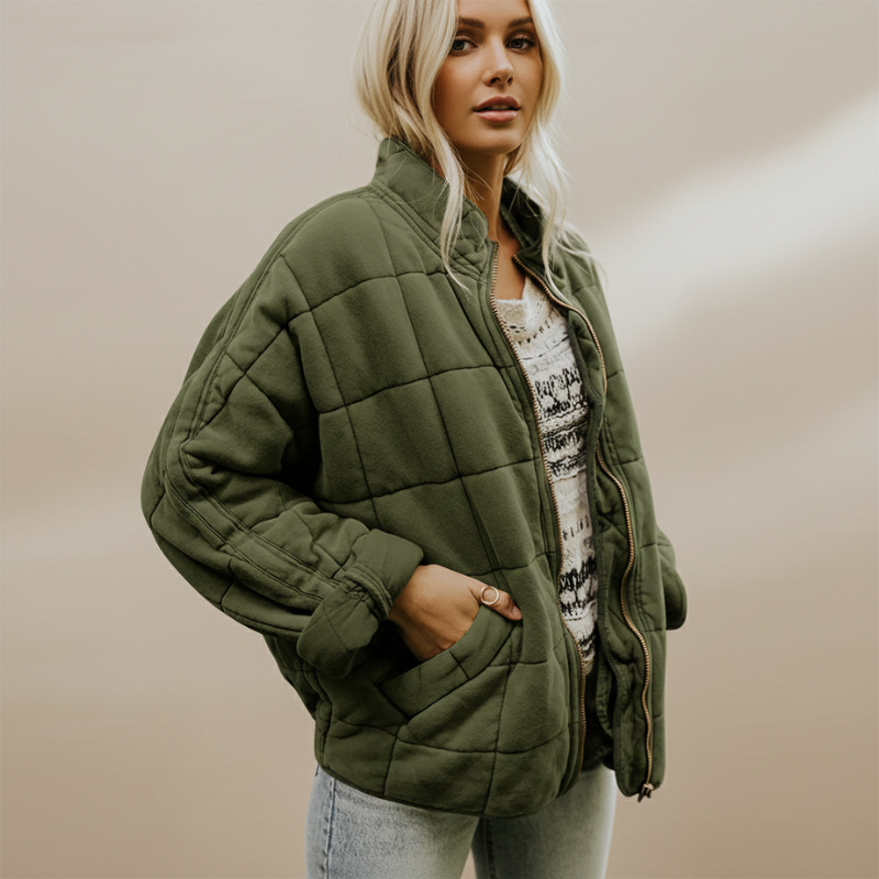 Model trägt eine olivgrüne Steppjacke mit lockerer Passform und funktionalen Details in einem hellen Innenraum.