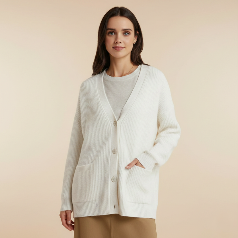 Model präsentiert einen weißen Cardigan mit klarer Linienführung und weichem Strickdesign in einem sonnendurchfluteten Raum.