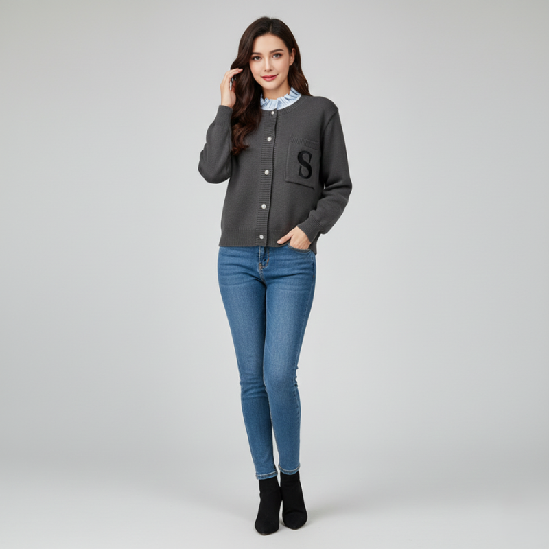 Modell trägt eine schwarze Strickjacke mit Knopfleiste und schmaler Silhouette, kombiniert mit Jeans im hellen Studio.