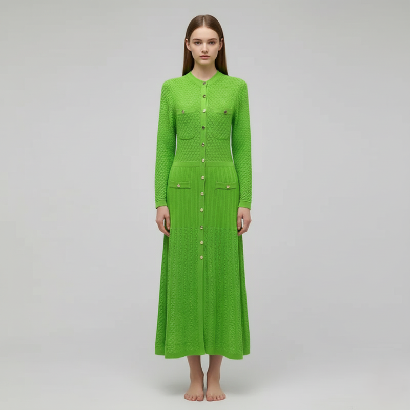 Model zeigt ein grünes langes Strickkleid mit dekorativen Knöpfen und leicht ausgestellter Form im Studio.