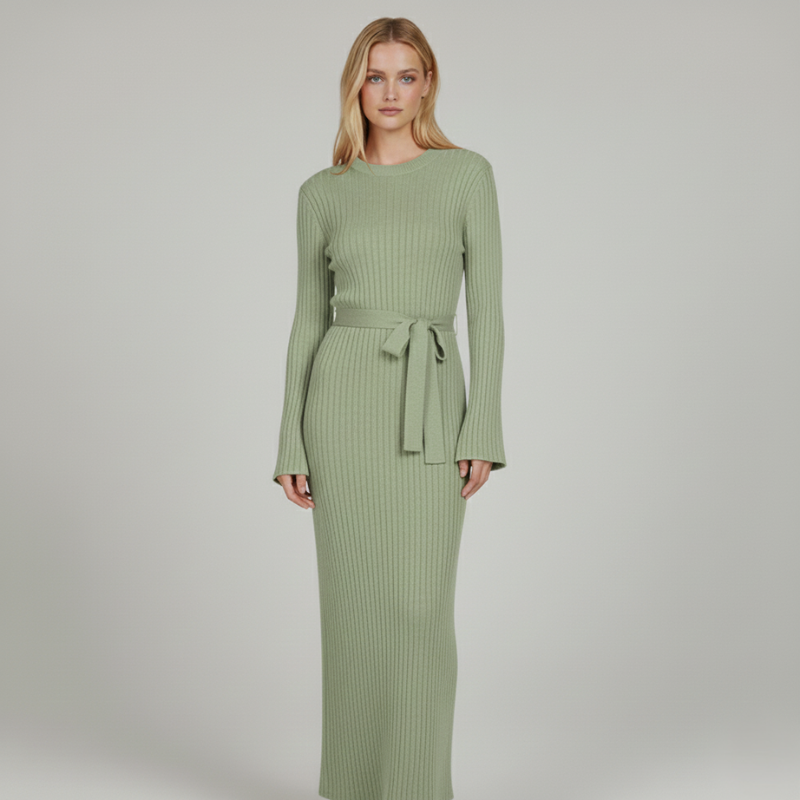 Model trägt ein langes grünes Strickkleid mit Rippenstruktur, Bindegürtel und figurbetonter Silhouette im Studio.