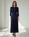 Model trägt ein navyblaues langes Strickkleid mit goldenen Knöpfen und eleganter Passform im hellen Studio.