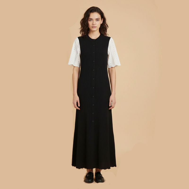 Model trägt ein langes schwarzes Strickkleid mit ärmellosem Design, gerippter Struktur und eleganter Silhouette vor neutralem Hintergrund.