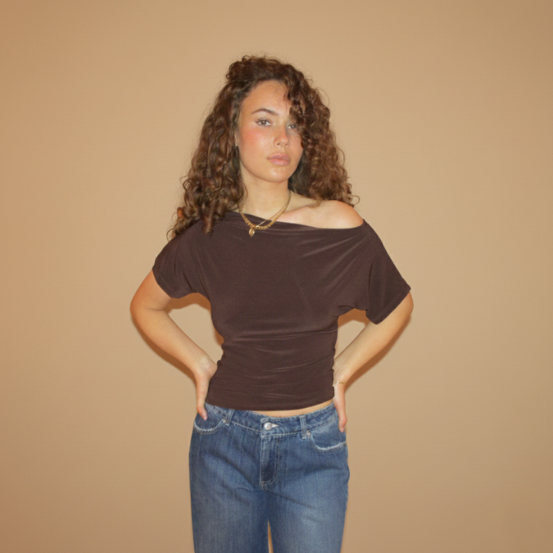 Model trägt ein braunes Kurzarmtop mit elegantem Faltenwurf und schlichter, körpernaher Linienführung im Studio.