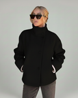 Schwarze Wolljacke mit hohem Kragen, glatter Struktur und lockerer Passform, präsentiert im neutralen Studio.